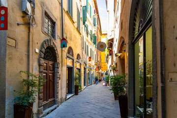 Fototapeta na wymiar A picturesque narrow alley or street of shops, businesses and apartments in the historic center of Lucca, Italy in the Tuscany region.