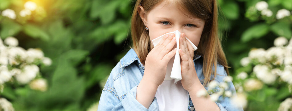 Little girl suffering from seasonal spring allergy outdoors. Banner design
