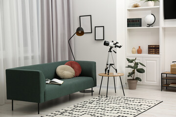 Tripod with modern telescope on table in living room