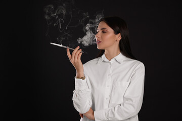 Woman using long cigarette holder for smoking on black background