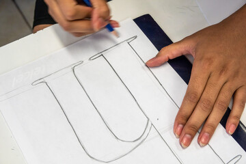 A person drawing a letter with a pencil 