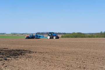 The tractor drives across the field and cultivates the land. Agricultural vehicle works in...