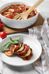 Delicious ratatouille served with basil on white marble table, closeup