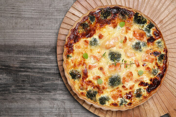 Delicious homemade quiche with salmon and broccoli on wooden table, top view. Space for text