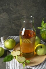 Delicious cider, ripe apples and green leaves on gray table