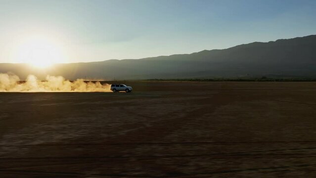 SUV Driving Across The Dusty Dry Lagoon Of Sayula During Golden Hour In Jalisco, Mexico. - aerial approach