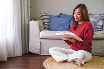 Portrait image of a young woman reading a book at home