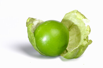 green tomatillo on white table covered with the peel