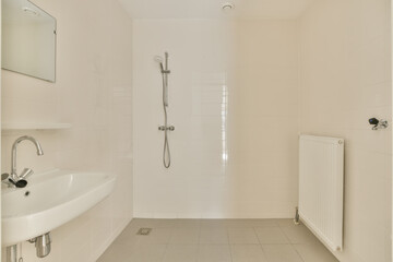 a bathroom with white tile flooring and wall mounted shower mixers in the corner of the bathtub is next to the sink