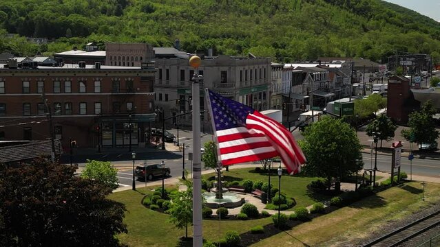 Aerial of USA flag flapping in breeze with small town of Tamaqua Pennsylvania in background