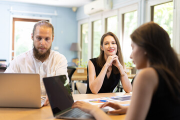 Business team using laptop and tablet presentation meeting. Sales Marketing Group is analyzing investment market. Male manager shows marketing analysis graph on tablet to female assistant.