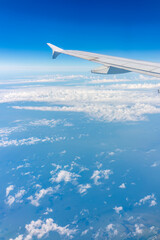 View from the airplane window at a beautiful cloudy sky and the airplane wing