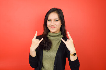 Smiling and showing metal music hands Of Beautiful Asian Woman Isolated On Red Background