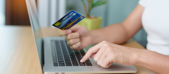 woman hand holding credit card and using laptop for online shopping while making order at home. Marketplace platform website, technology, ecommerce, digital banking and online payment concept
