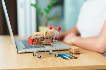 woman hand holding credit card and using laptop with mobile phone for online shopping while making...