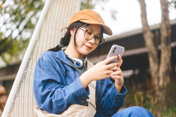 Woman wearing denim jacket typing with smartphone for online message or dating app technology at...