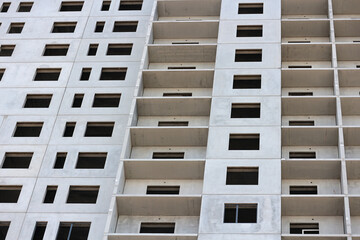 Windows and balconies of an abstract unfinished apartment building under construction. Urban background.
