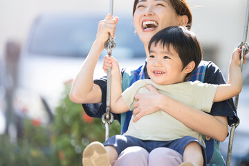 ブランコで一緒に遊ぶ笑顔の保育士と笑顔の幼児