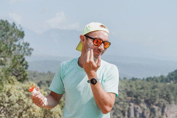 Hiker sporty man sky runner applying sun cream to protect skin from dangerous uv sun rays high in...