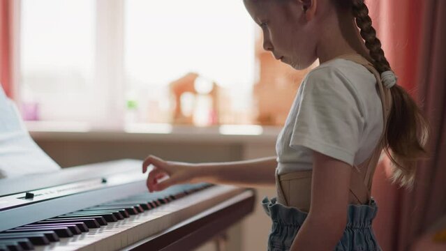 Diligent girl plays electronic piano with right hand