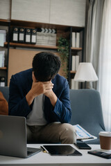 Frustrated young businessman working on a laptop computer sitting at his working place in office.