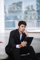 Asian businessman using a tablet on a bench in the city