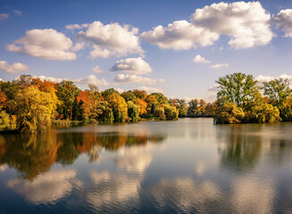 Ruhiger See mit Wasserspiegelung und einem Wald in herbstlichen Farben