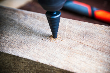 Stepped conical drill on a wooden background close-up.