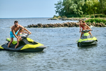 Father, mother, daughter and son racing on jet-skis enjoying watercraft in ocean.
