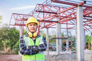 Engineer standing with arms crossed In front of the house building work and the roof is not yet finished