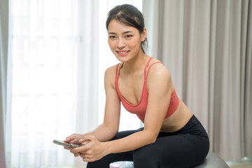 Fototapeta na wymiar Beautiful woman exercising fitness at home and talking to mobile phone, Home interior, Fitness mat.