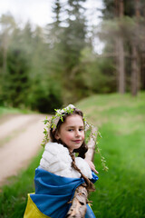 Ukrainian child girl with the flag of Ukraine in the forest