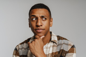 Fototapeta premium Young brunette man in shirt looking aside with suspicion
