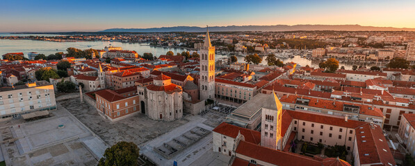 Zadar, Croatia - Aerial panoramic view of the Forum of the old town of Zadar with the Church of St. Donatus and the bell tower of the Cathedral of St. Anastasia on a summer morning with golden sunrise - obrazy, fototapety, plakaty