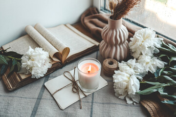 Obraz na płótnie Canvas Burning candle and white peonies, vintage aesthetic