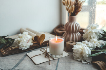 Naklejka na ściany i meble Burning candle and white peonies, vintage aesthetic