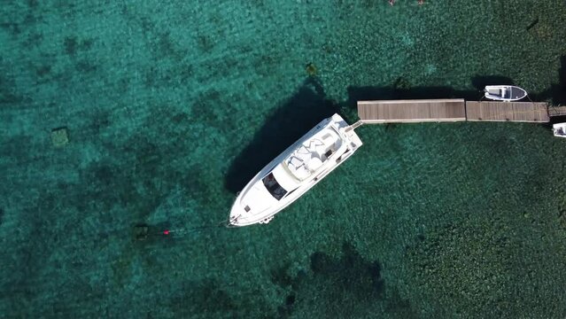 Ferretti Speedboat Yacht moored to Mooring Buoy at wooden Jetty dock in Blue Lagoon of Veliki Budikovac, Croatia. Aerial