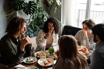 Group of cheerful friends talking while dining in restaurant