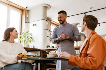 Smiling waiter serving couple in cafe