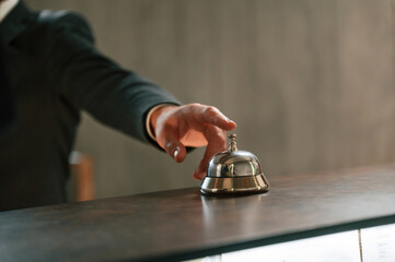Close up view, using hotel desk bell. A man in a black jacket at the hotel reception