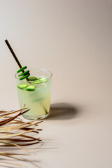 Eine selbstgemachte Limonade mit Gurken auf ienem beigen Tisch. Palmwedel, Sommer.