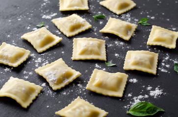 Raw Ravioli with Flour and Basil on Dark Background