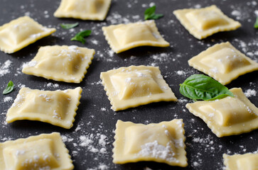 Raw Ravioli with Flour and Basil on Dark Background