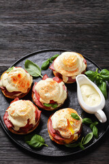 Eggs Benedict on black plate, top view