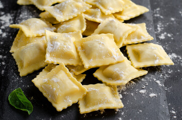 Raw Ravioli with Flour and Basil on Dark Background