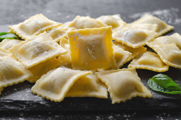 Raw Ravioli with Flour and Basil on Dark Background