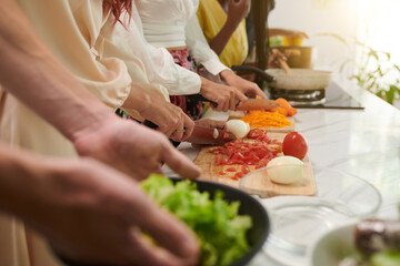Hands of people cutting vegetables when cooking meal at culinary class