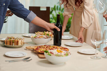 Man putting bottle of wine on dinner table