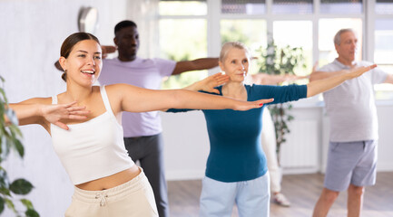 Fototapeta premium Enthusiastic young girl practicing hip-hop movements during adult group dance class in studio