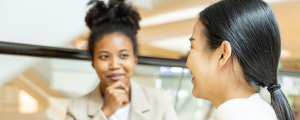 Asian woman talking fluently with her African friend or co-worker, concept image of good command in foreign language in real life situation